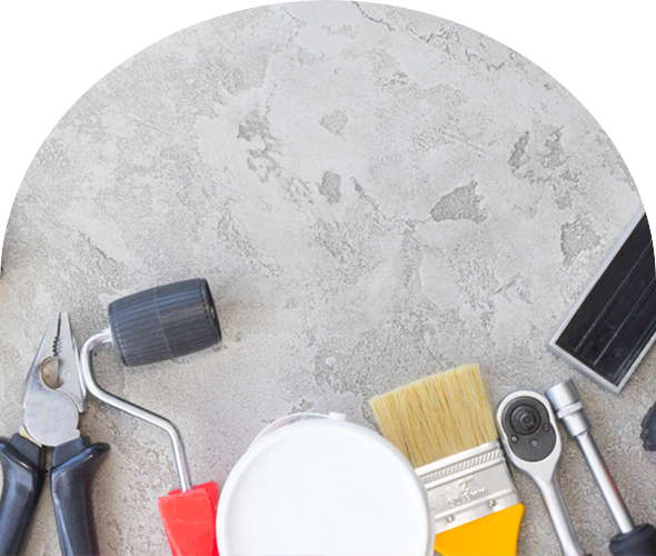 Painting tools arranged on a gray surface, including rollers, brushes, and a paint can.